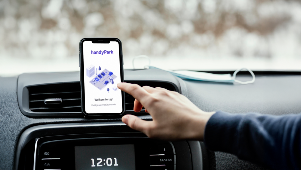 Chauffeur van een auto klikt op app HandyPark op zijn boordcomputer.