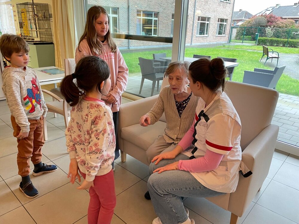 Kinderen spelen met een oudere dame en een verzorgende in een woonzorgcentrum