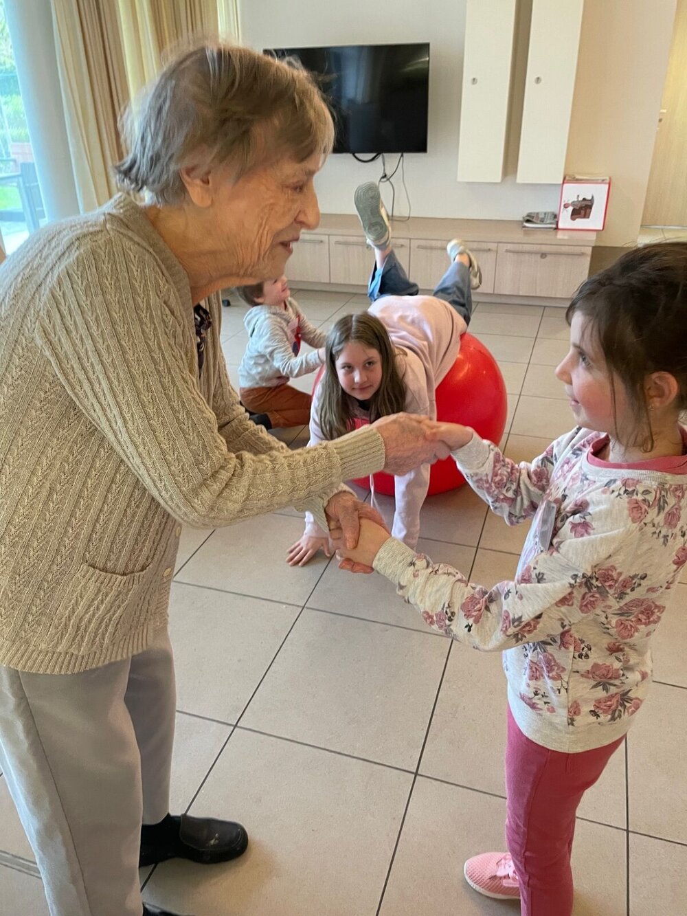 Oudere dame danst met jonge kinderen in een woonzorgcentrum