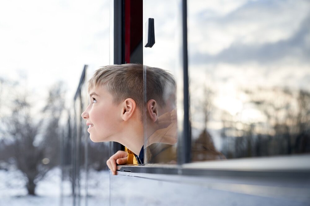 Jongen kijkt verwachtingsvol uit rijdende trein naar het landschap