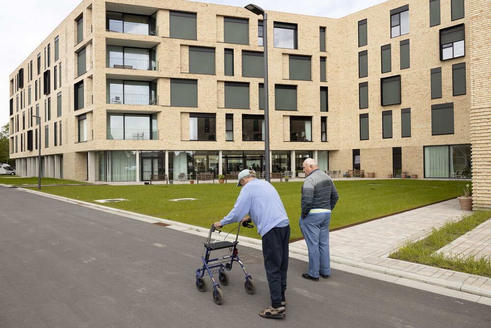 Exterieurbeeld van een woonzorgcentrum met in de voorgrond twee mannen. 