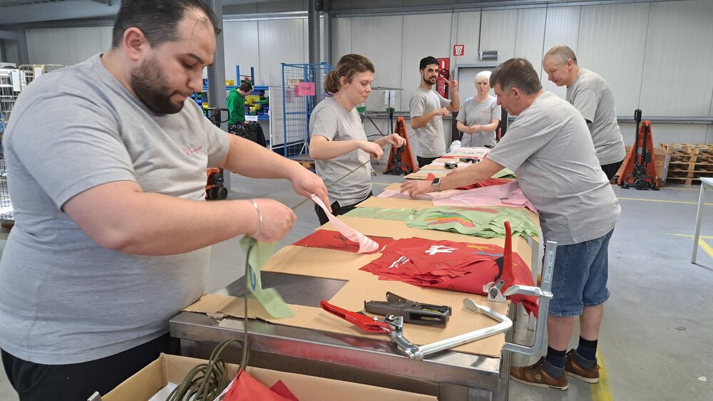 Meerdere mensen werken aan textiel op een tafel