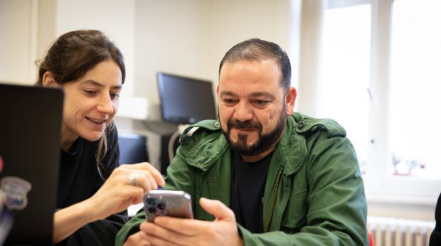 Een vrouw helpt een man bij het werken op de smartphone