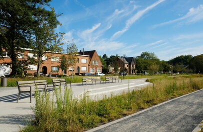 Zicht op inrit naar fort Mortsel met bankjes, gevels van huizen en groen