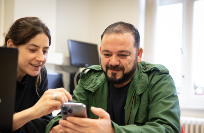 Een vrouw helpt een man bij het werken op de smartphone