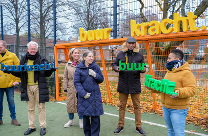 een groepje buren die de letters buurkracht vasthouden