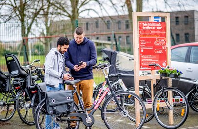man geeft uitleg aan gebruiker bij enkele deelfietsen
