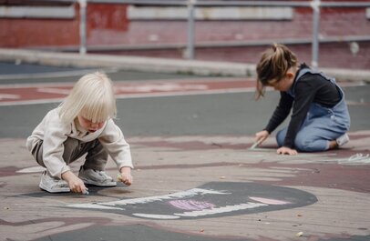 Twee kinderen spelen met krijt op een speelplaats
