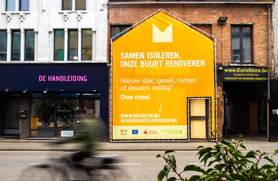 foto van rijwoningen met grote affiche in de vorm van een van de woningen