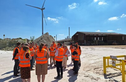 foto van groepje mensen op bezoek op de site met windturbine