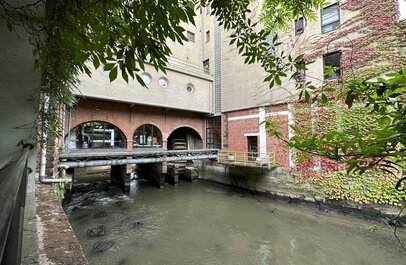 Aquathermie systeem. Stalen buizen die over het water gaan tussen 2 gebouwen.
