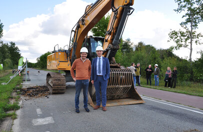 burgemeesters Wim Dries van stad Genk en Johny De Raeve van de gemeente Zonhoven poseren voor een graafmachine