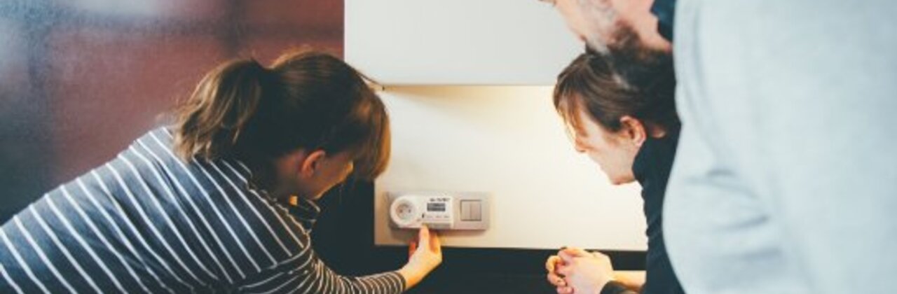 drie mensen krijgen uitleg over werking thermostaat