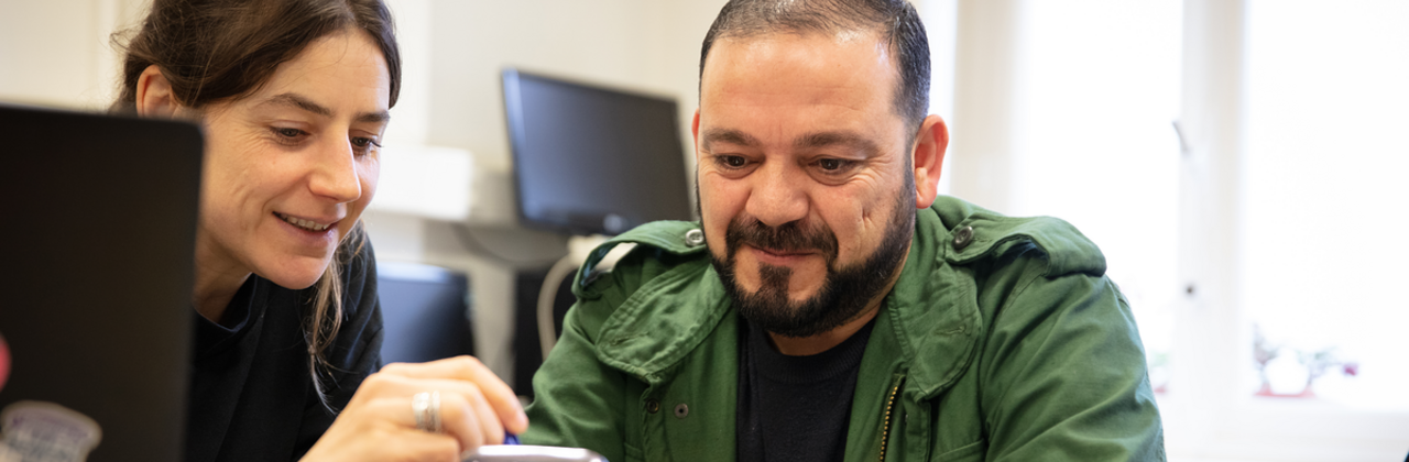 Een vrouw helpt een man bij het werken op de smartphone