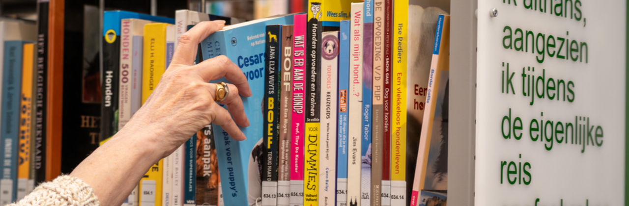 hand die boek vastpakt in boekenrek bibliotheek
