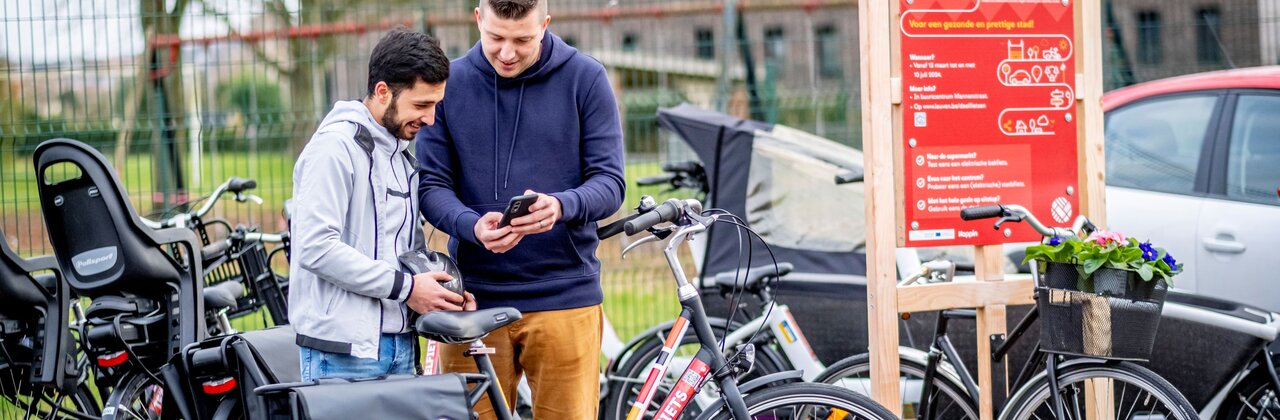 man geeft uitleg aan gebruiker bij enkele deelfietsen