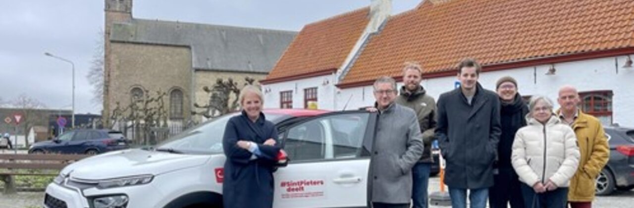 Een deelwagen met daarrond mensen.