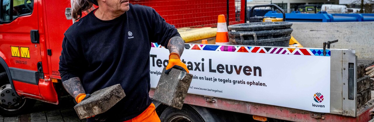 Man werpt straattegels in een laadbak van een vrachtwagen.