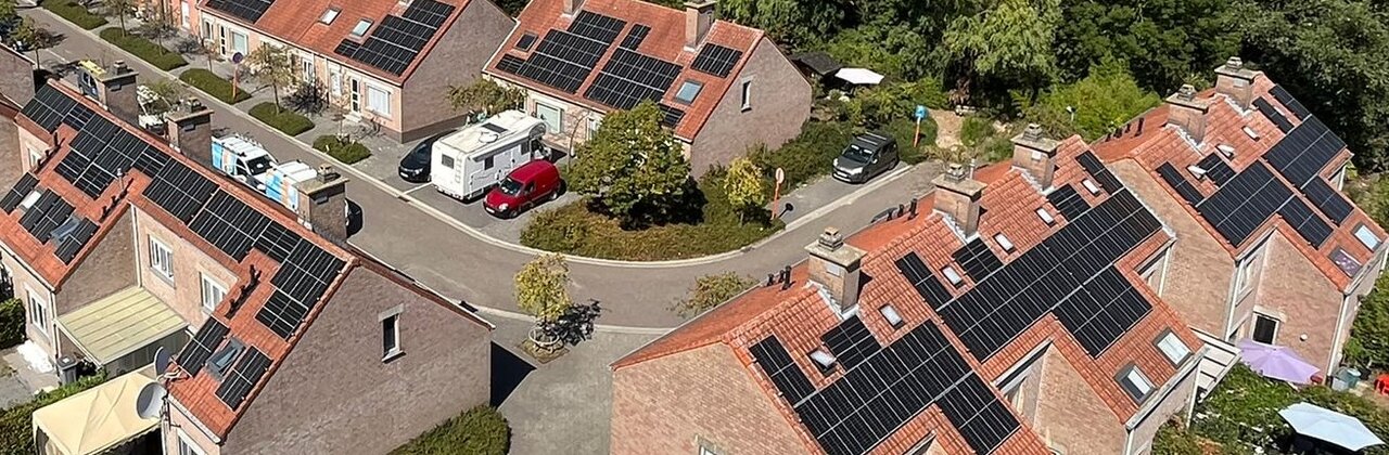 luchtfoto van een (sociale) woonwijk met daken met zonnepanelen