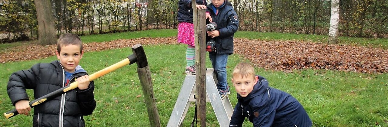Kinderen slaan met een voorhamer palen in de grond.