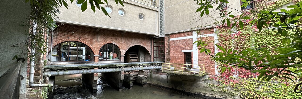 Aquathermie systeem. Stalen buizen die over het water gaan tussen 2 gebouwen.