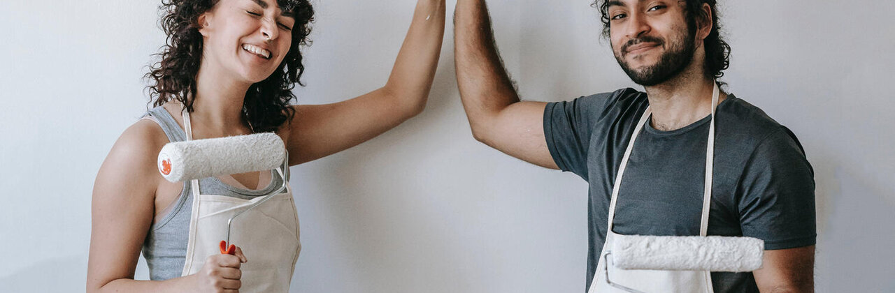 twee mensen (met verfborstel in de hand) doen een high-five