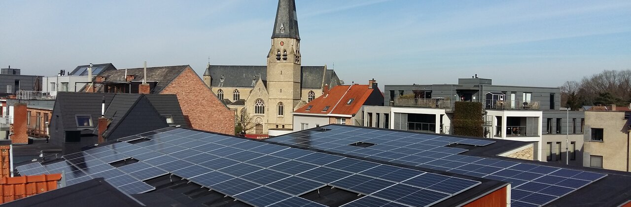 Dak met zonnepanelen met op achtergrond kerktoren Bonheiden.