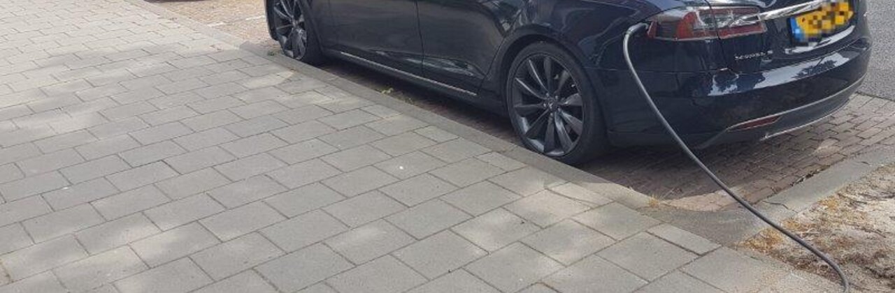 foto van voetpad met kabelgoottegels, ingeplugde wagen