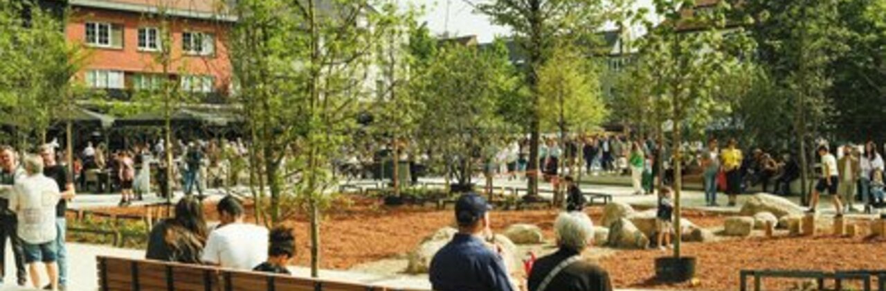 Grote Markt met in het midden veel bomen en aan de kant mensen die op bankjes zitten