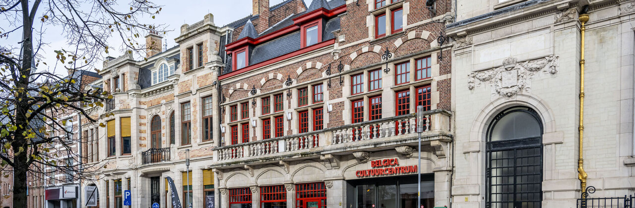 De afbeelding toont een straat met historische gebouwen, waaronder trapgevels, en een open plein met moderne elementen.