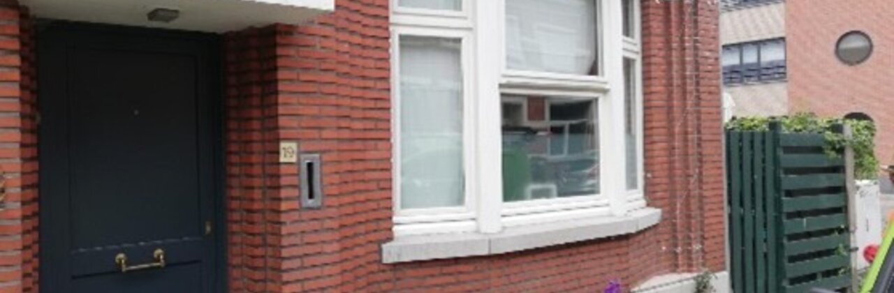 Deze afbeelding toont een huis met een voortuin waarbij een rij stoeptegels vervangen werd door een tegeltuintje.
