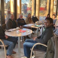 Mensen rond een tafel om Nederlands te leren