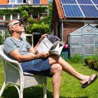 man in tuin met daarachter woning met zonnepanelen