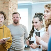 5 mensen die luisteren naar iemand die iets vertelt