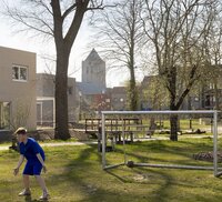 Groen veld met voetbalgoal en kindjes die spelen