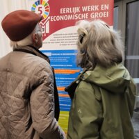 Burgers bekijken SDG-banners op de infomarkt over het MJP