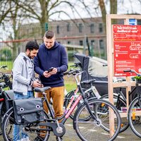 man geeft uitleg aan gebruiker bij enkele deelfietsen