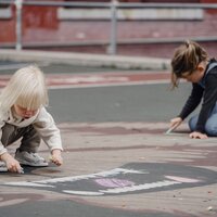 Twee kinderen spelen met krijt op een speelplaats