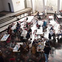 zaal met groepen mensen aan tafels