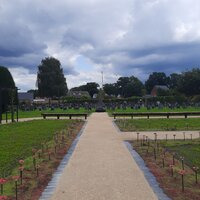 Vooraanzicht van de begraafplaats met langs beide zijden groen en achteraan grafstenen.