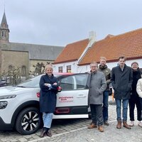 Een deelwagen met daarrond mensen.