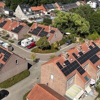 luchtfoto van een (sociale) woonwijk met daken met zonnepanelen