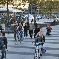 foto van winkelstraat met fietsers, voetgangers en geparkeerde wagens