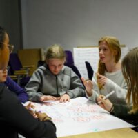 Mensen die samen zitten rond een papier waar zaken op geschreven zijn