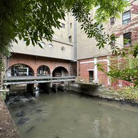 Aquathermie systeem. Stalen buizen die over het water gaan tussen 2 gebouwen.