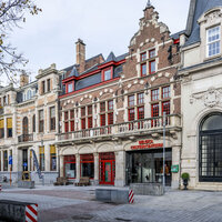 De afbeelding toont een straat met historische gebouwen, waaronder trapgevels, en een open plein met moderne elementen.