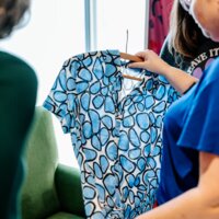 Een vrouw bekijkt een tweedehands jurk